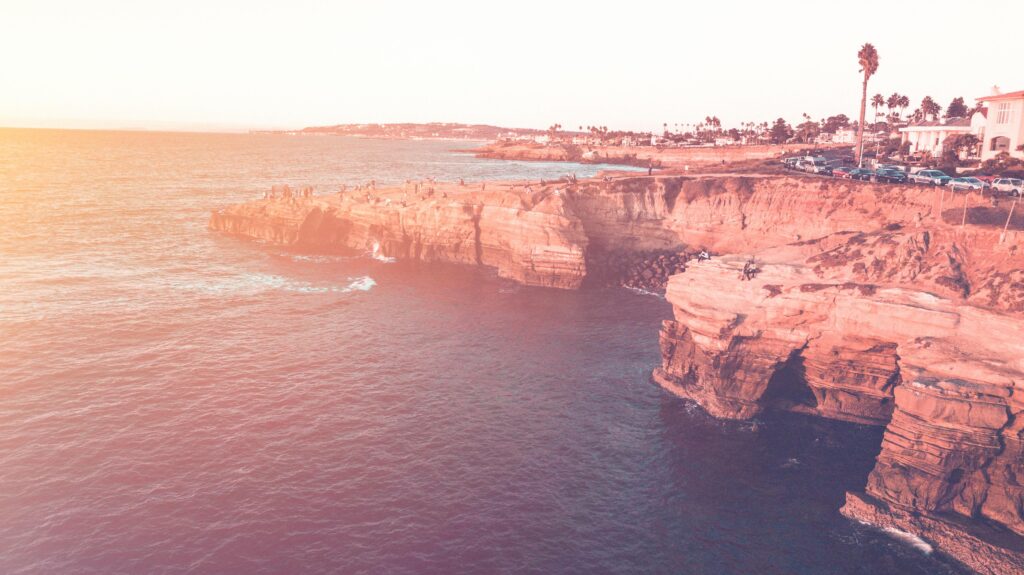 Stunning aerial capture of San Diego cliffs and ocean during a vibrant sunset, showcasing natural beauty.
